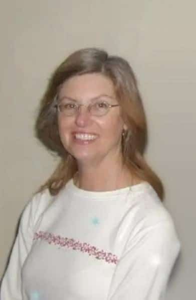 Kathleen Mary Rohr wears glasses and a white sweater. She is smiling.