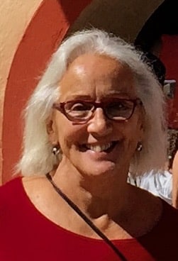 A portrait photo of Martina. She is smiling, wearing glasses and a red shirt.